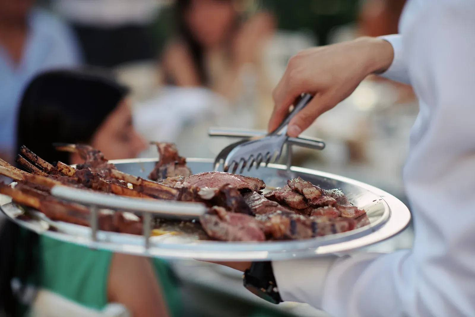 Waiter serving grilled lamb ribs at a catering event